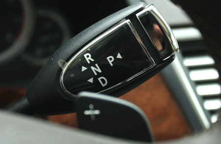Cần số gắn trên vô-lăng của Mercedes E300. Khi cần chuyển sang chế độ bán tự động, tài xế chỉ cần ấn cần có dấu 