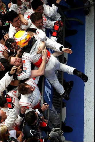 Các thành viên của McLaren bủa vây Hamilton để chúc mừng chiến thắng đầu tay của McLaren